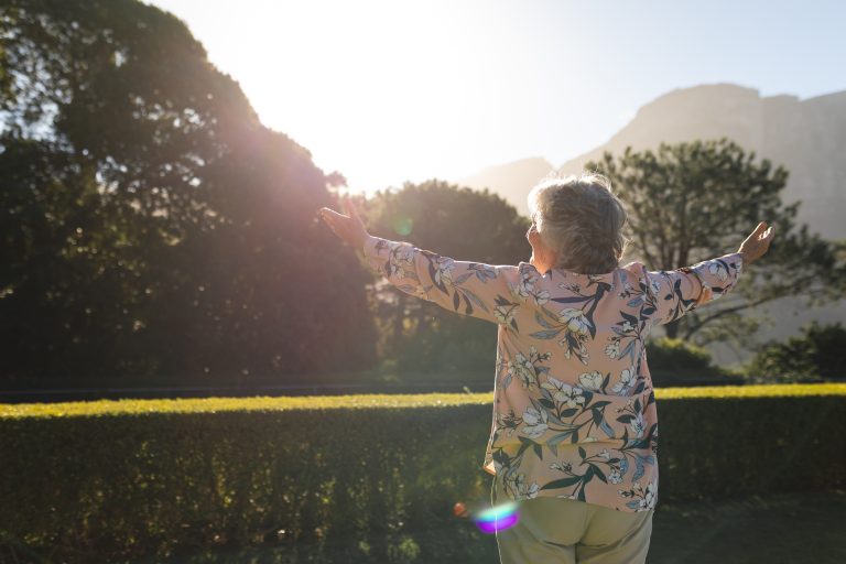 Happy senior caucasian woman with arms outstretched in sunny garden. luxury retirement lifestyle, spending time alone at home