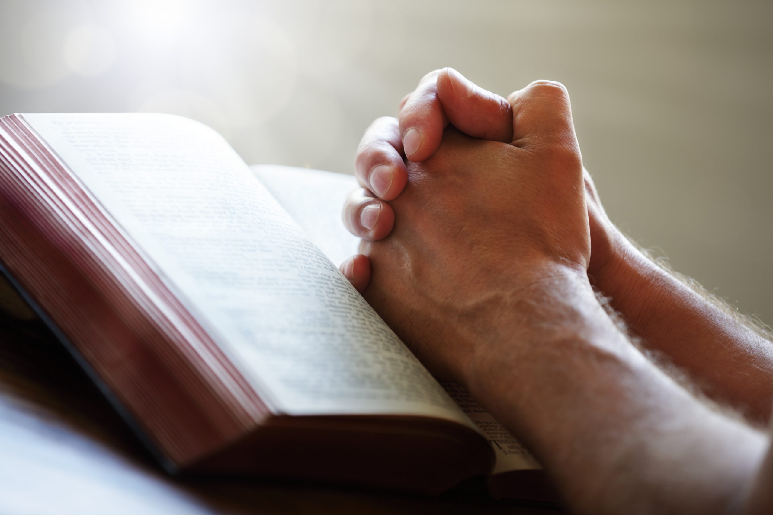 Hands folded in prayer on a Holy Bible